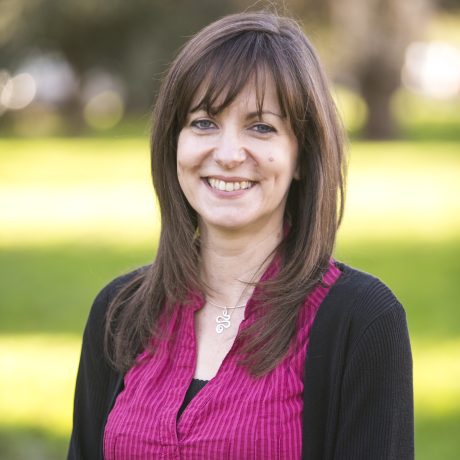 Anita Holford smiling at the camera. She is wearng a purple top, black cardigan and has long brown hair.