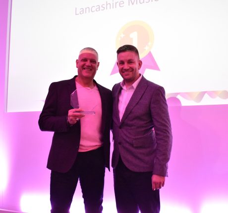 Two men stood smiling holding an award