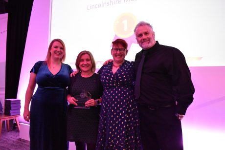 Four people stood smiling holding a glass award