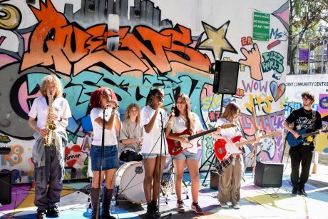 A group of young people playing instruments performing on stage outdoors