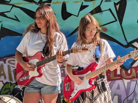 Two young people playing red guitars outside