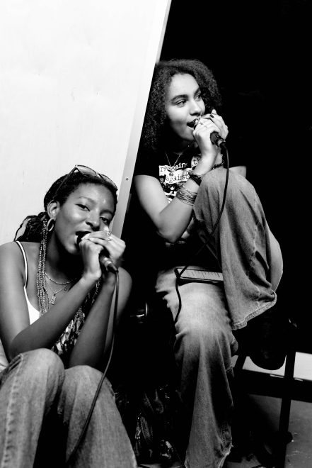 Two young people singing into microphones, black and white