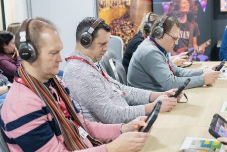 Three men using tablets wearing headphones.