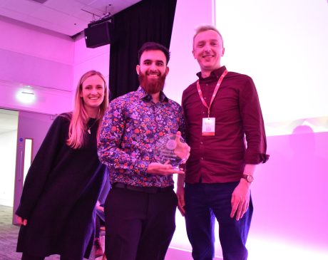 Three people stood smiling holding a glass award