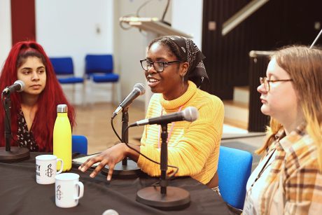 Three young people sat round a table, with microphones in front of them.