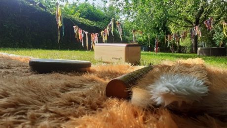 A soft blanket on the floor that looks like fox fur, with some instruments on top of the blanket. In the background you can see grass and trees with hanging fabric around.