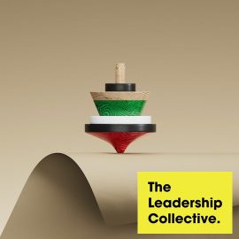 A wooden spinning top balancing on a brown worktop that merges into a brown gradient background. 'The Leadership Collective' inset on the bottom right on a yellow background.